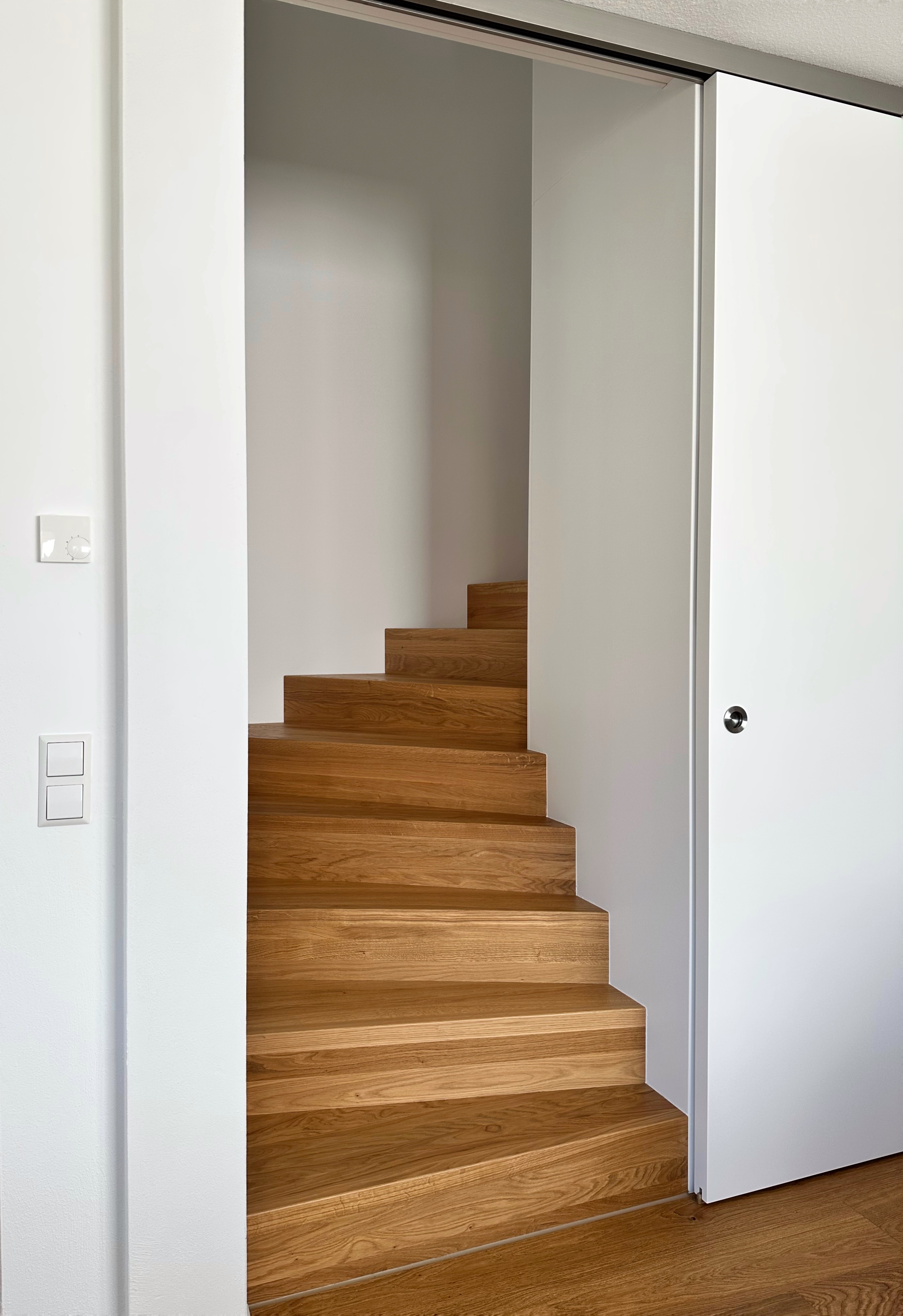 Massive Holzstufen in einer gewendelten Treppe mit integriertem Schrank im Treppenauge