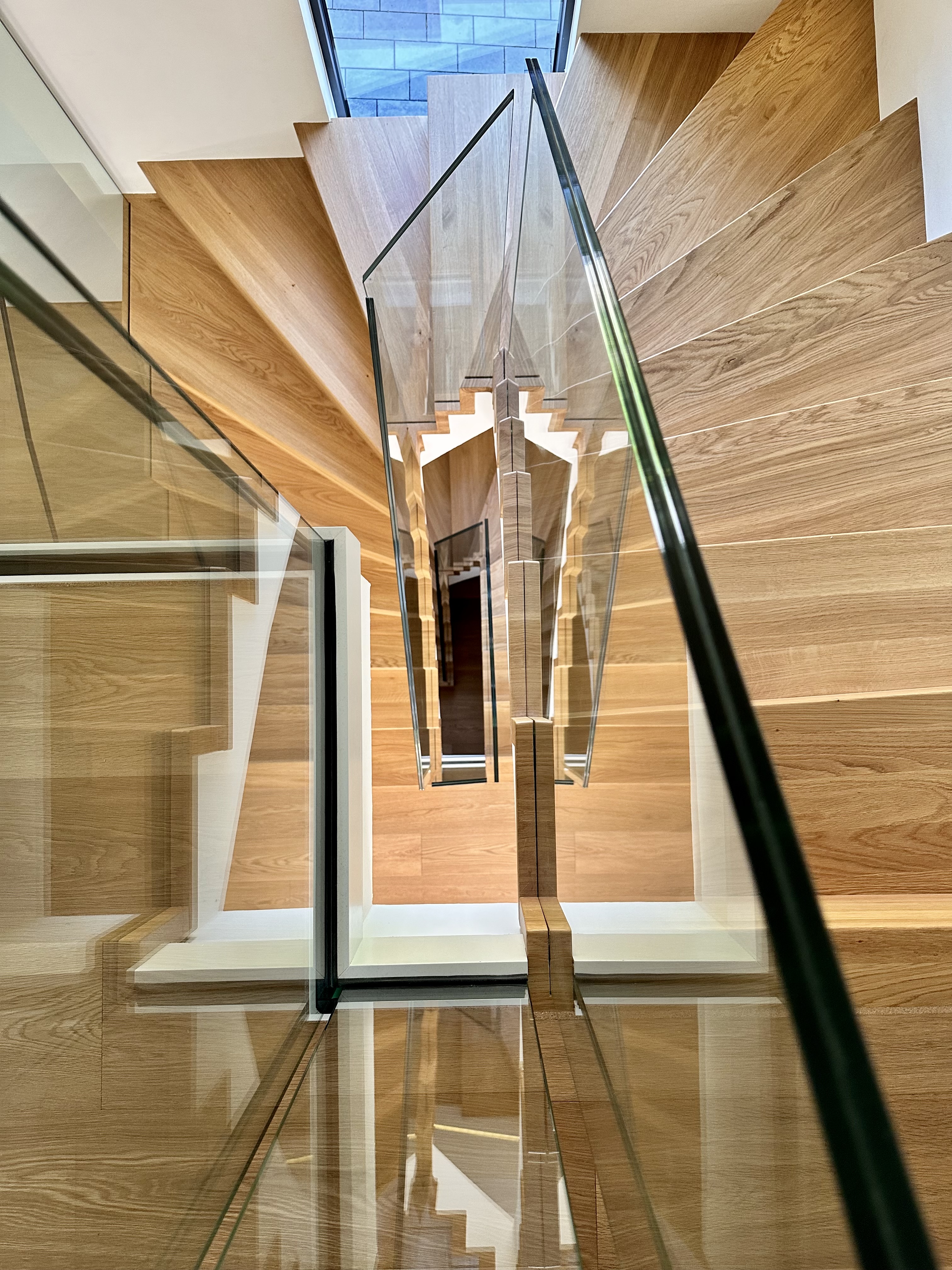 Moderne Treppenarchitektur mit lichtdurchflutetem Treppenauge und rahmenlosem Glasgeländer